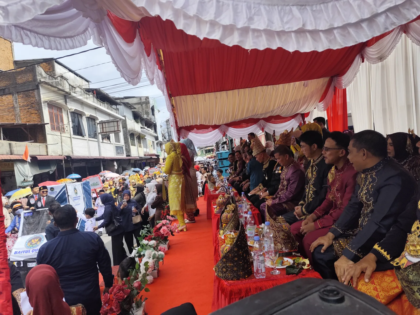 Pejabat Kabupaten Aceh Barat Daya berpakaian adat Aceh duduk di panggung kehormatan berhias merah putih saat menyaksikan peserta Pawai Budaya HUT ke-81 RI di Blangpidie, 16 Agustus 2026.